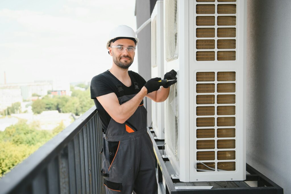 Young man repairman checking an outside air conditioner unit